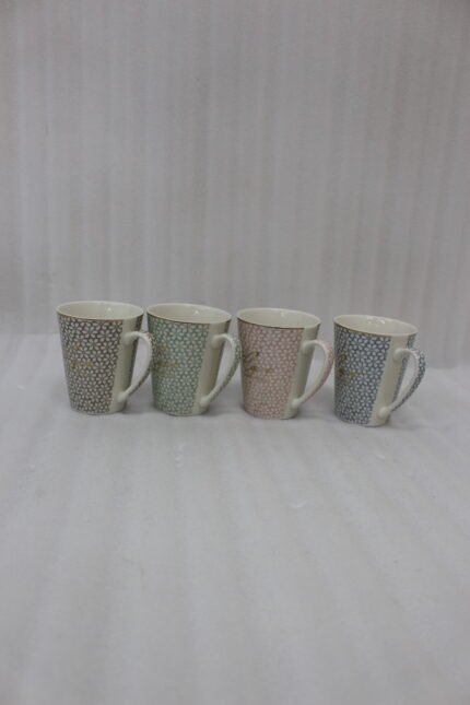 Four ceramic coffee mugs in beige, mint green, blush pink, and light blue with floral geometric patterns displayed on a marble countertop.
