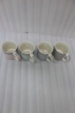 4-piece ceramic mug set in pink, green, and grey with polka dots, horizontal stripes, and gold rims on a kitchen countertop