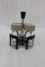 Four-piece clear glass spice jar set with lid options sitting in a black metal holder on a kitchen countertop.