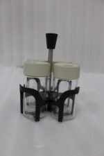 Four-piece clear glass spice jar set with lid options sitting in a black metal holder on a kitchen countertop.