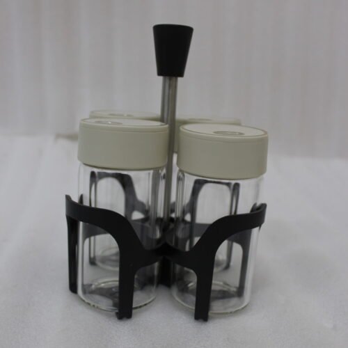 Four-piece clear glass spice jar set with lid options sitting in a black metal holder on a kitchen countertop.