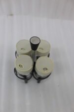 Four-piece clear glass spice jar set with lid options sitting in a black metal holder on a kitchen countertop.