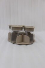 Four modern 6-piece revolving glass spice jar sets with gold trim lids displayed on a white kitchen countertop in beige, cream, black, and white colors.