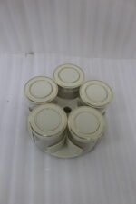 Four modern 6-piece revolving glass spice jar sets with gold trim lids displayed on a white kitchen countertop in beige, cream, black, and white colors.