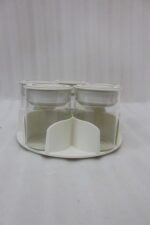 Four modern 6-piece revolving glass spice jar sets with gold trim lids displayed on a white kitchen countertop in beige, cream, black, and white colors.