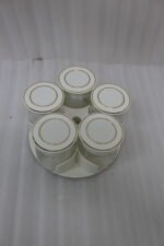 Four modern 6-piece revolving glass spice jar sets with gold trim lids displayed on a white kitchen countertop in beige, cream, black, and white colors.