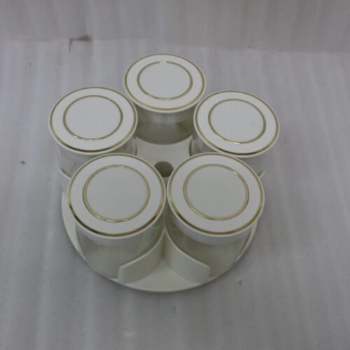 Four modern 6-piece revolving glass spice jar sets with gold trim lids displayed on a white kitchen countertop in beige, cream, black, and white colors.