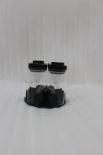 Four-piece clear glass spice jar sets with airtight lids displayed on rotating organizer trays in black, beige, tan, and white on a marble kitchen countertop.