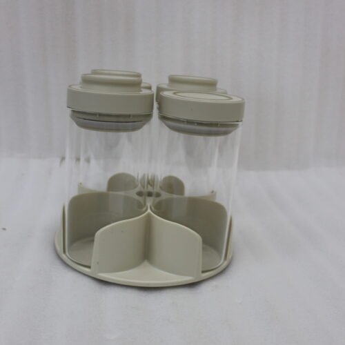 Four-piece clear glass spice jar sets with airtight lids displayed on rotating organizer trays in black, beige, tan, and white on a marble kitchen countertop.
