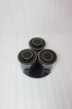Four sets of ONE MORE 3-piece glass spice jars with trays sitting on a white marble countertop in beige, off-white, white, and black colors.