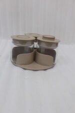Four sets of ONE MORE 3-piece glass spice jars with trays sitting on a white marble countertop in beige, off-white, white, and black colors.