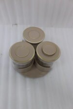 Four sets of ONE MORE 3-piece glass spice jars with trays sitting on a white marble countertop in beige, off-white, white, and black colors.