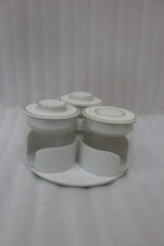 Four sets of ONE MORE 3-piece glass spice jars with trays sitting on a white marble countertop in beige, off-white, white, and black colors.