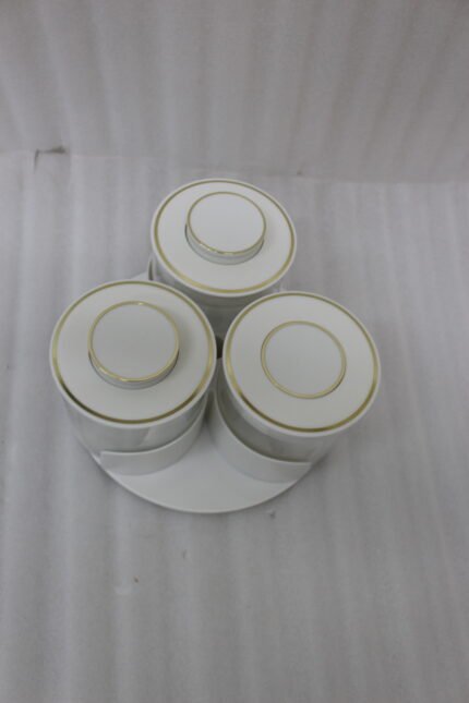 Four sets of ONE MORE 3-piece glass spice jars with trays sitting on a white marble countertop in beige, off-white, white, and black colors.