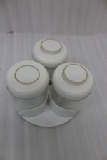 Four modern glass spice jar sets in black, tan, cream, and off-white with gold lid rings arranged on a marble kitchen countertop.