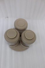 Four modern glass spice jar sets in black, tan, cream, and off-white with gold lid rings arranged on a marble kitchen countertop.