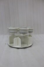 Modern rotating spice rack organizer set with 6 clear glass jars and gold-accented lids on a granite kitchen countertop.