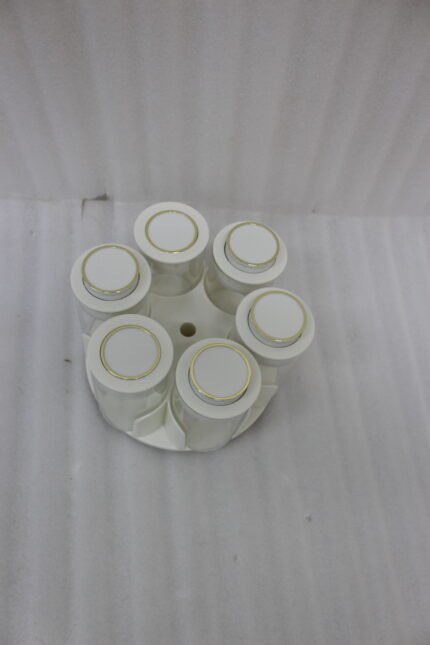 Modern rotating spice rack organizer set with 6 clear glass jars and gold-accented lids on a granite kitchen countertop.
