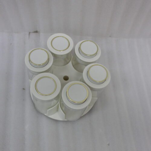 Modern rotating spice rack organizer set with 6 clear glass jars and gold-accented lids on a granite kitchen countertop.