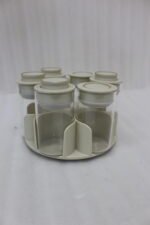 Modern rotating spice rack organizer set with 6 clear glass jars and gold-accented lids on a granite kitchen countertop.