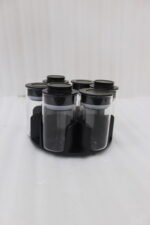 Modern rotating spice rack organizer set with 6 clear glass jars and gold-accented lids on a granite kitchen countertop.