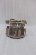 Modern rotating spice rack organizer set with 6 clear glass jars and gold-accented lids on a granite kitchen countertop.