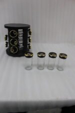 Modern 12-piece rotating black and gold spice rack organizer with glass jars on a white marble kitchen countertop