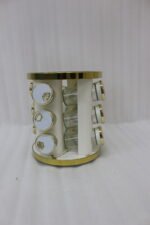 Modern 12-piece rotating black and gold spice rack organizer with glass jars on a white marble kitchen countertop