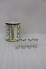 Modern 12-piece rotating black and gold spice rack organizer with glass jars on a white marble kitchen countertop