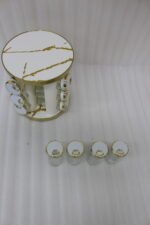 Modern 12-piece rotating black and gold spice rack organizer with glass jars on a white marble kitchen countertop