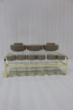 A 9-piece glass spice jar set with matte brown lids and gold-tone metal rack sitting on a granite countertop.