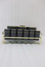 9-piece matte black and gold luxury spice rack set with clear glass bottoms on a granite countertop.