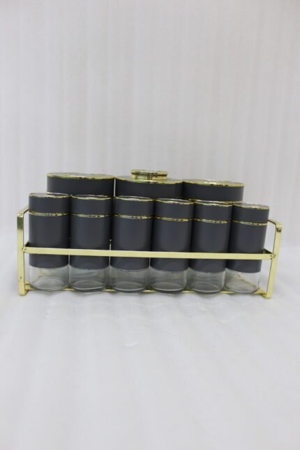 9-piece matte black and gold luxury spice rack set with clear glass bottoms on a granite countertop.
