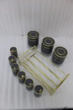 9-piece matte black and gold luxury spice rack set with clear glass bottoms on a granite countertop.