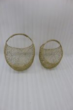 Set of two gold woven wire metal decorative baskets with coiled handles displayed on a wooden table