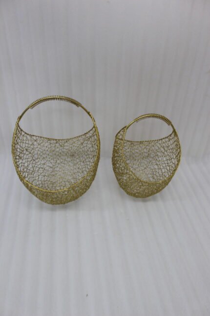 Set of two gold woven wire metal decorative baskets with coiled handles displayed on a wooden table