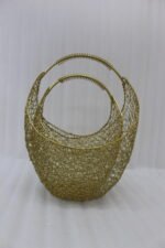 Set of two gold woven wire metal decorative baskets with coiled handles displayed on a wooden table
