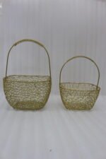 Two gold mesh metal decorative baskets with coiled top handles on a wooden table.