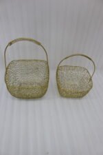 Two gold mesh metal decorative baskets with coiled top handles on a wooden table.