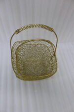 Two gold mesh metal decorative baskets with coiled top handles on a wooden table.