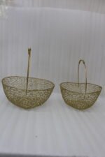 Two heart-shaped decorative gold wire mesh baskets with single handles set on a wooden table.