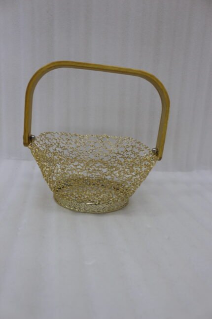 Gold woven wire decorative basket with a natural wooden handle sitting on a wooden tabletop