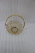 Gold decorative metal mesh basket with a curved wooden handle placed on a wooden table in a bright modern dining room