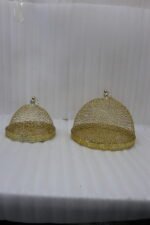 Two gold decorative metal wire mesh dome cloche covers sitting on a wooden table.