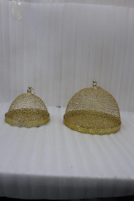 Two gold decorative metal wire mesh dome cloche covers sitting on a wooden table.