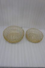Set of two round gold woven wire decorative metal baskets sitting on a light wooden tabletop.