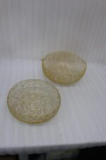 Set of two round gold woven wire decorative metal baskets sitting on a light wooden tabletop.
