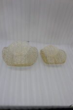 Two gold woven wire decorative metal baskets sitting on a light wooden tabletop.