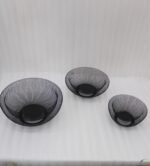Set of two modern black wire mesh decorative baskets sitting on a wooden kitchen island countertop.