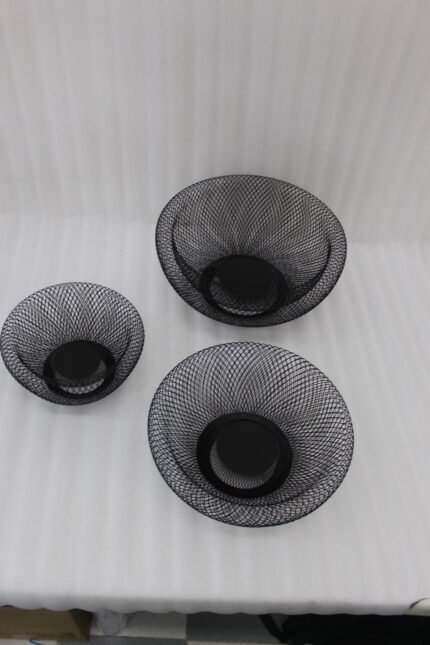 Set of three round black wire mesh decorative metal baskets displayed on a wooden kitchen countertop.